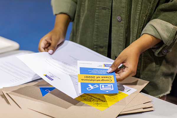 A person's hands organizing a graduate certificate package.