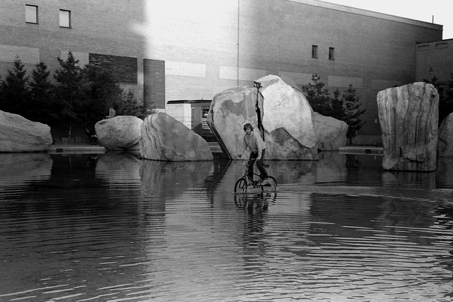 A young man rides a bicycle through Lake Devo in 1982