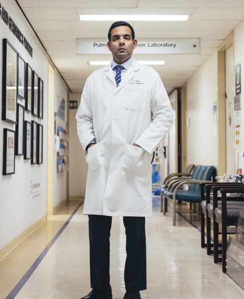Dr. Samir Sinha stands wearing a white lab coat in the hospital hallway