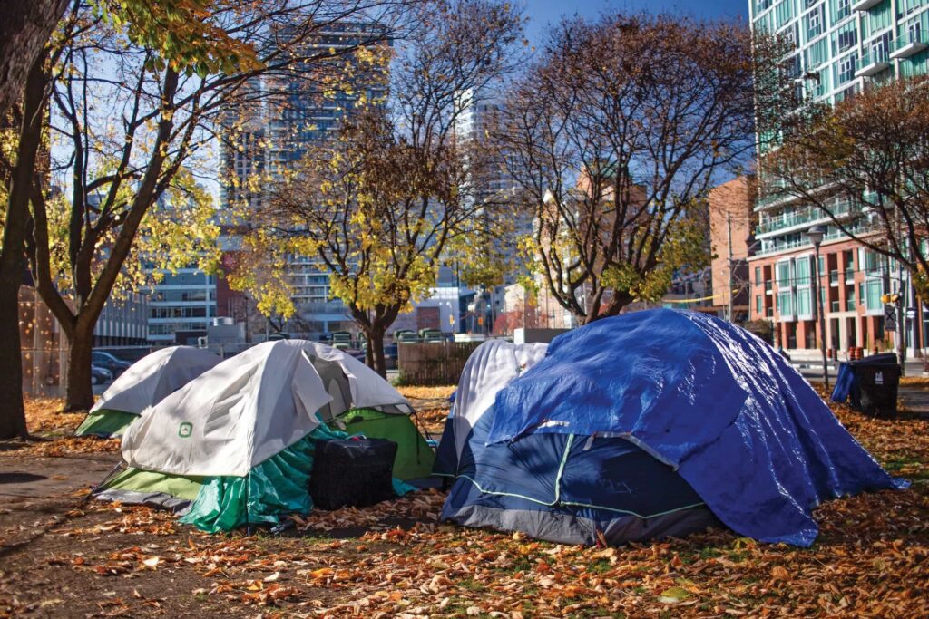 Two tents set up in a Toronto park surrounded by buildings and trees