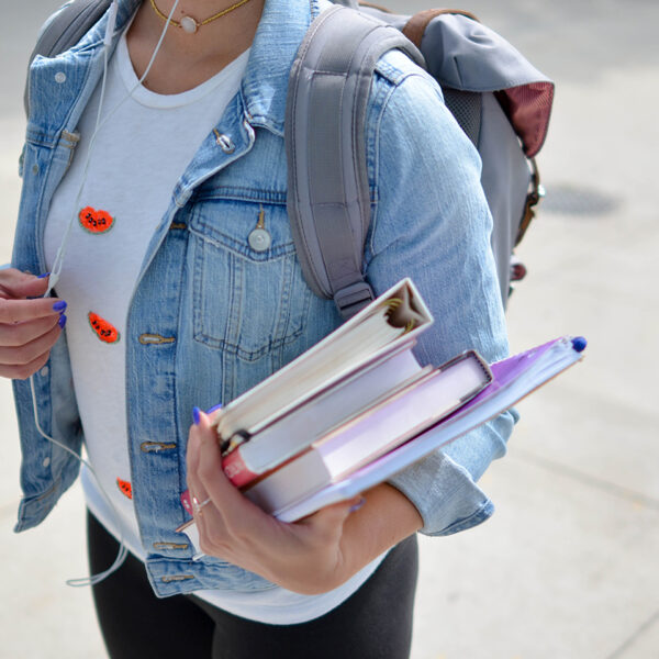 A student holding a set of textbooks.