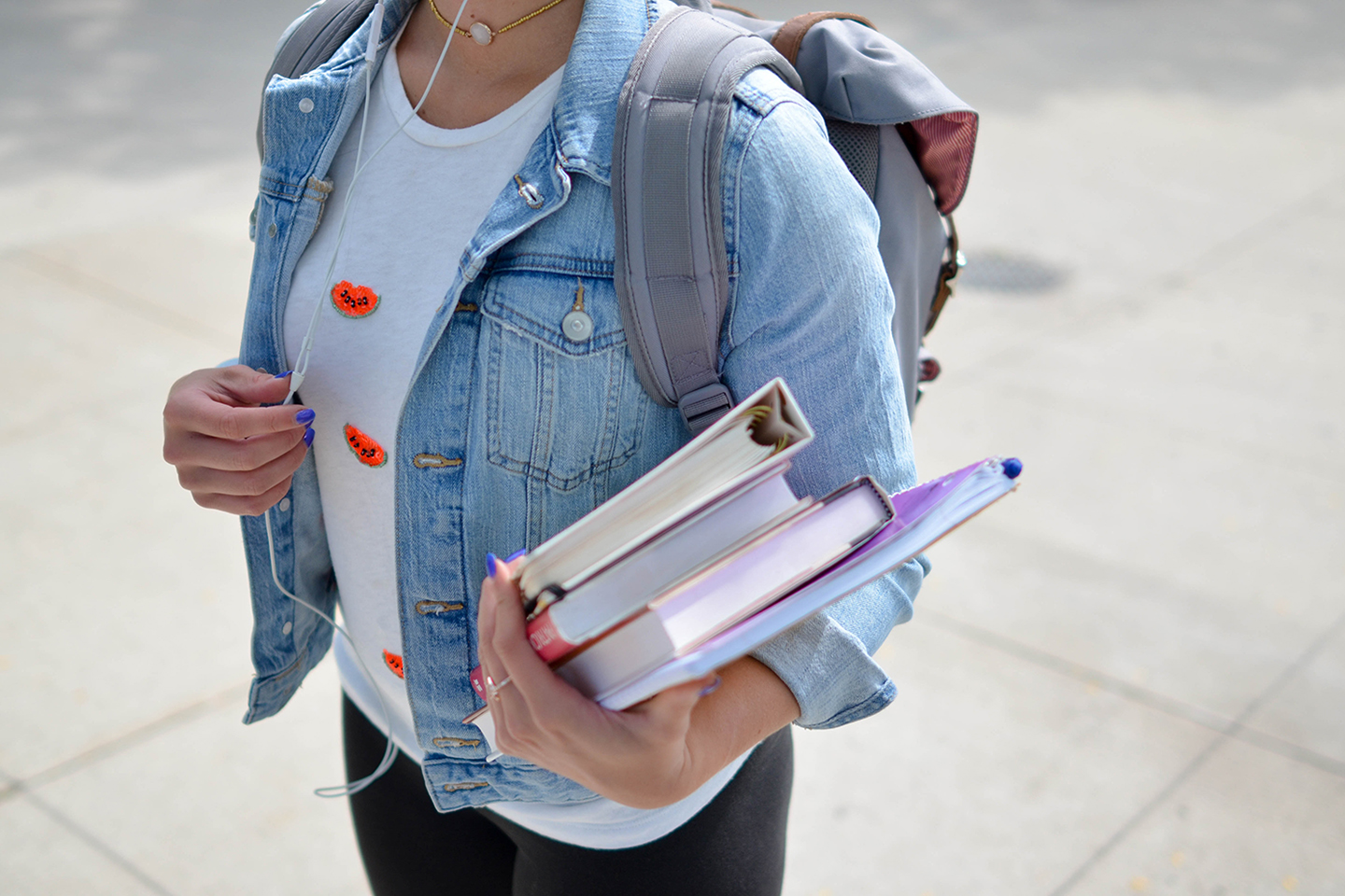 A student holding a set of textbooks.