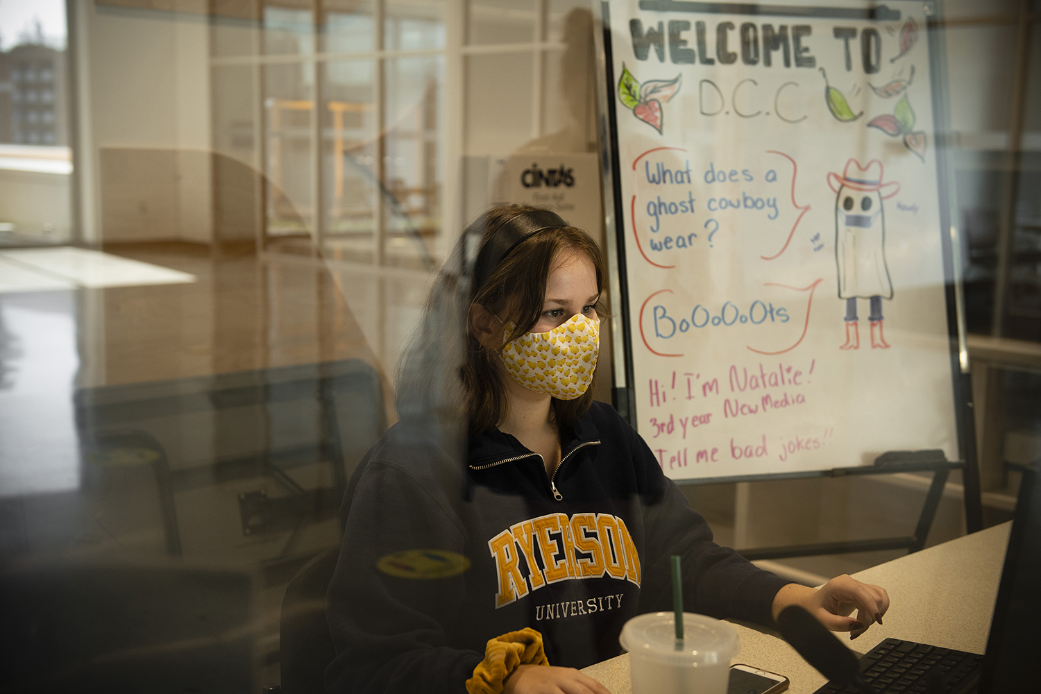 A receptionist sits at the computer with a mask on.