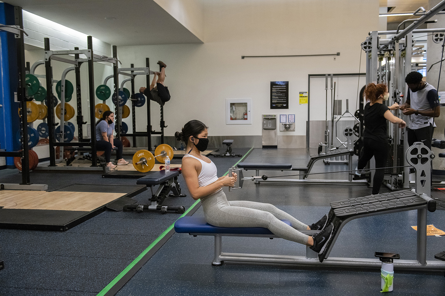 A female student working out in the gym with a mask on.