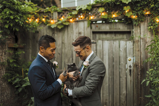 Two men getting married hold their cat.