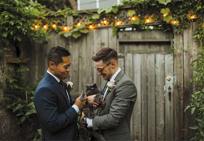 Two men getting married hold their cat.