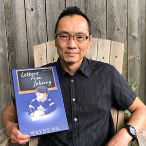 Wayne Ng holding his book, Letters from Johnny.
