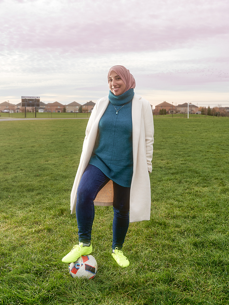 Shireen Ahmed stands on a soccer field with one foot on a soccer ball.