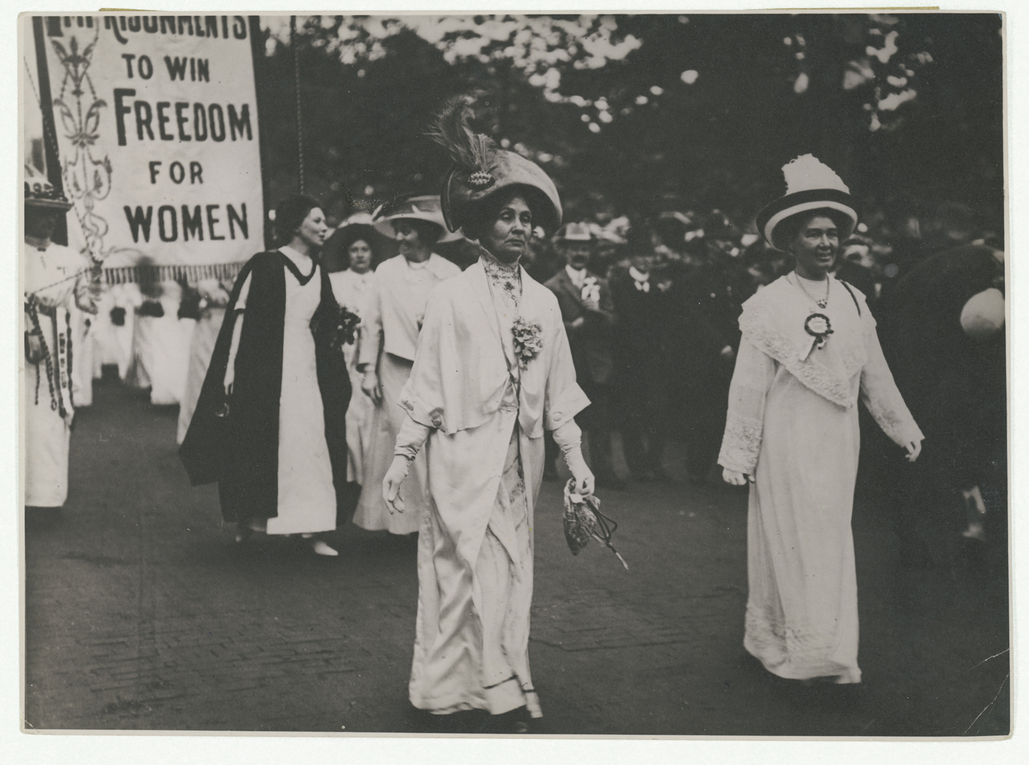 British Suffragettes walking down the street carrying signs.