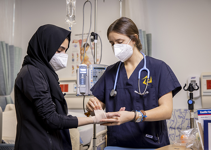 A student wraps a woman's arm in a bandage