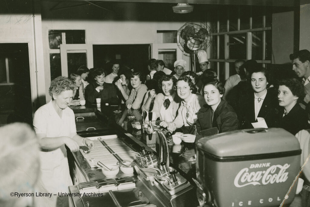 Black and white photo of people at the Tuck Shop in 1952-1953 school year.