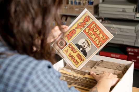A woman pulls a comic out of a box.