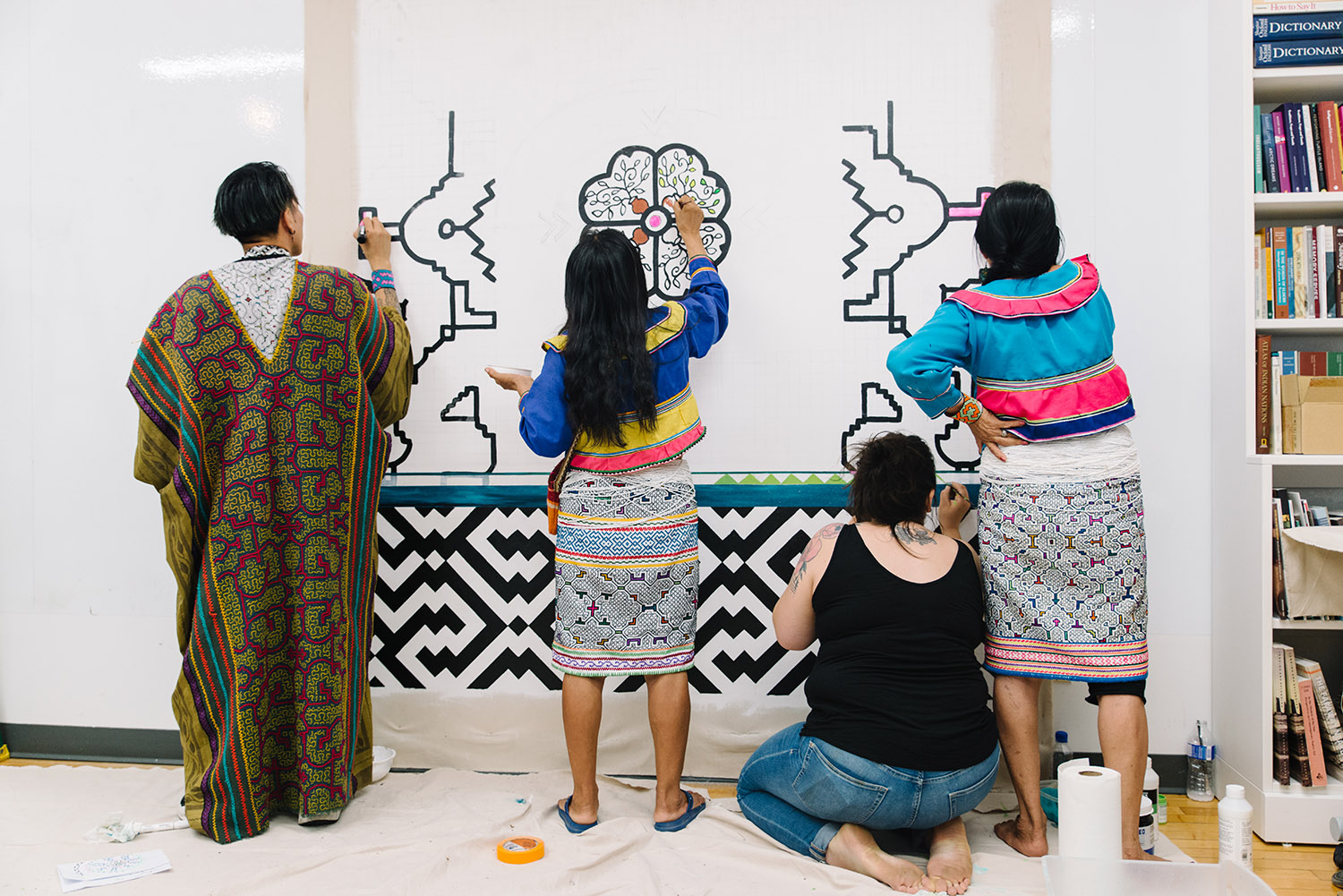 Indigenous artists are shown painting the new art mural.