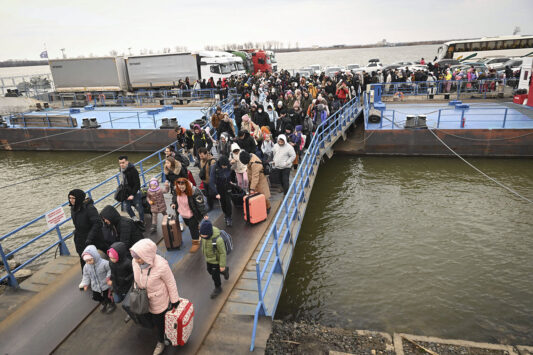 Migrants cross a bridge to a boat.