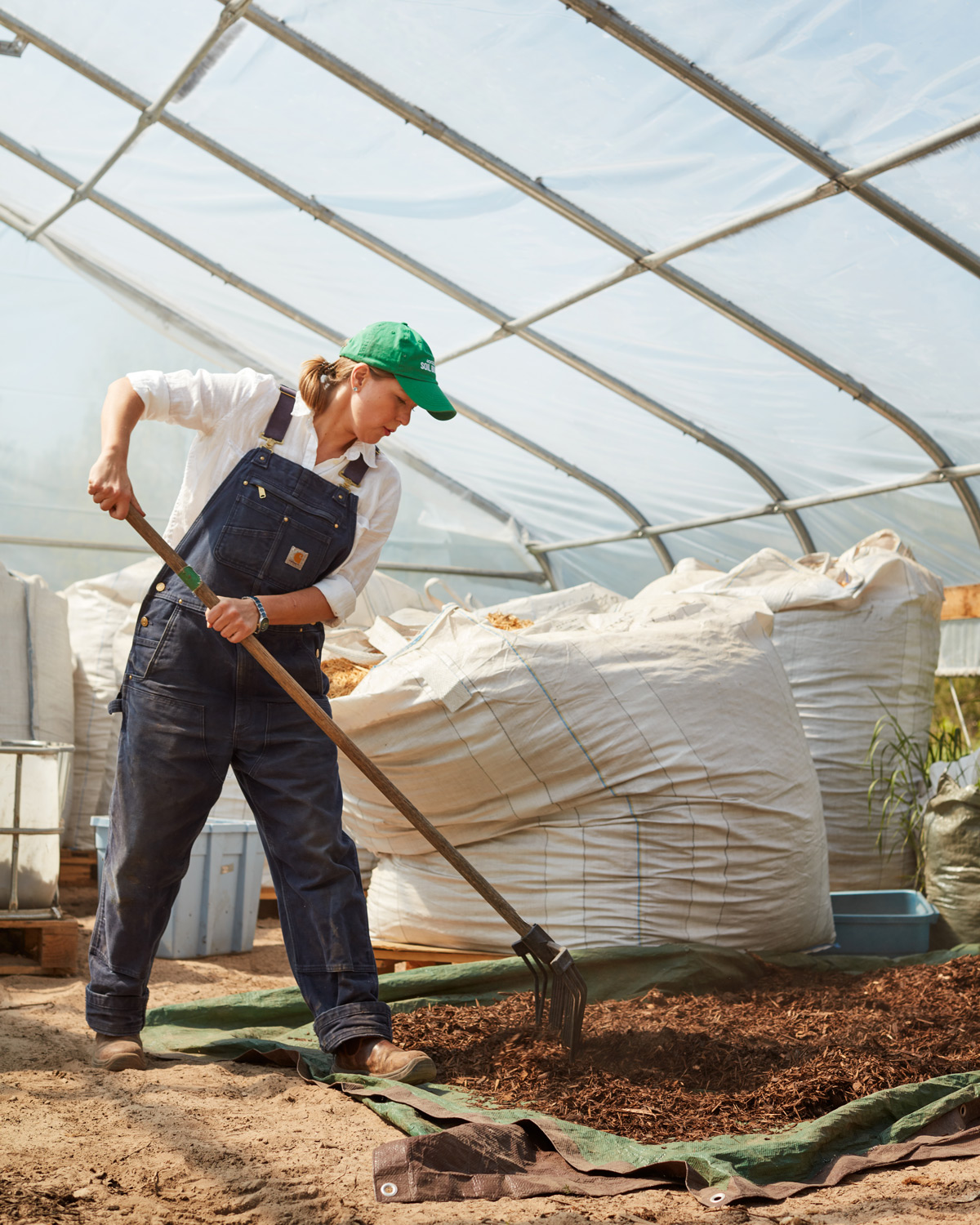 A woman gardening inside a greenhouse.