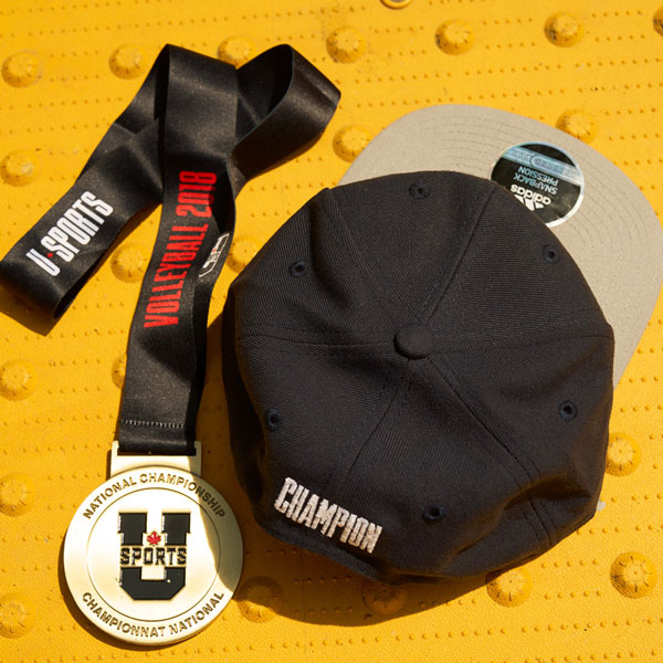 Championship memorabilia: Gold medal with a black ribbon that says “Volleyball 2018” and a black snapback hat with “champion” stitched on the back.