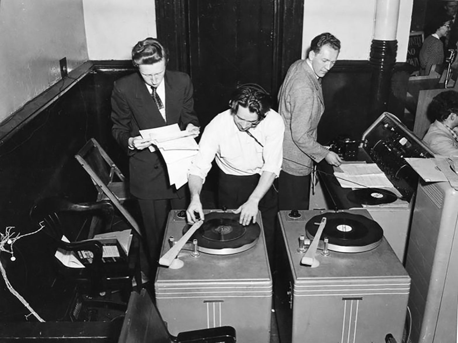Three students operating large turntables and looking at papers.