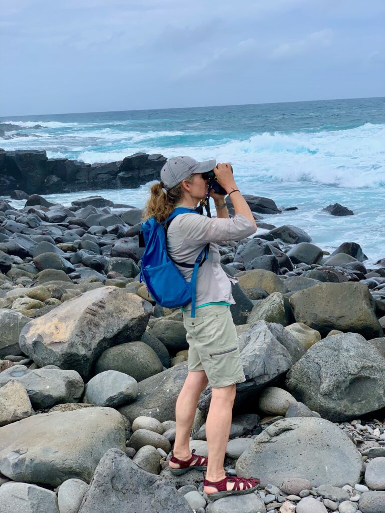 Nina-Marie Lister looking out into the ocean with binoculars.