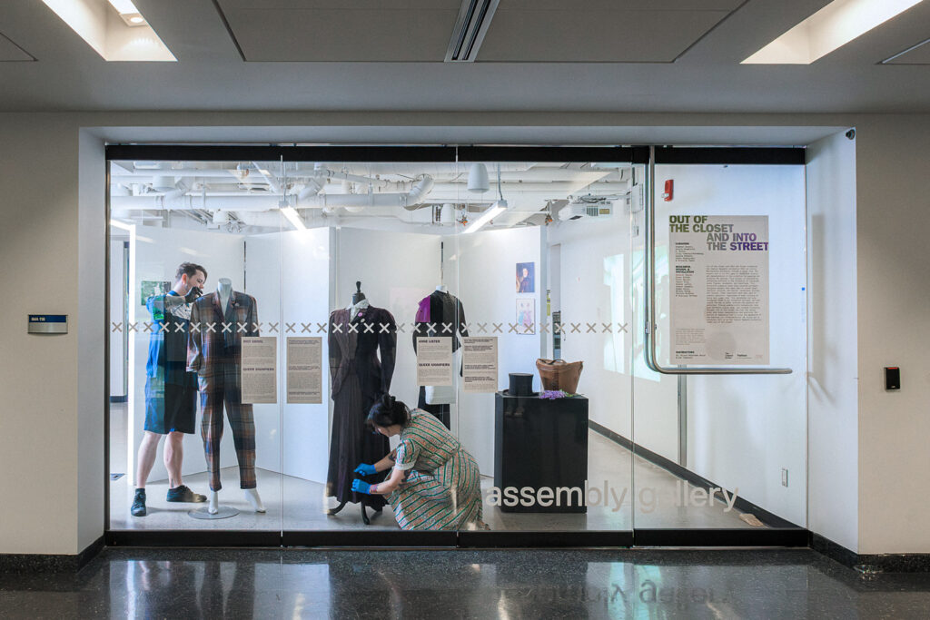 Researchers Patrick Taylor and Sonya Surbek dress mannequins behind a glass wall.