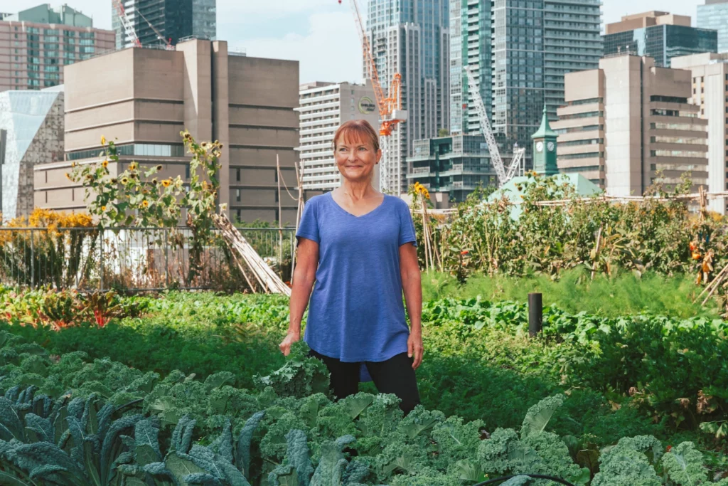 Kristiina Mai standing among plants in a garden.