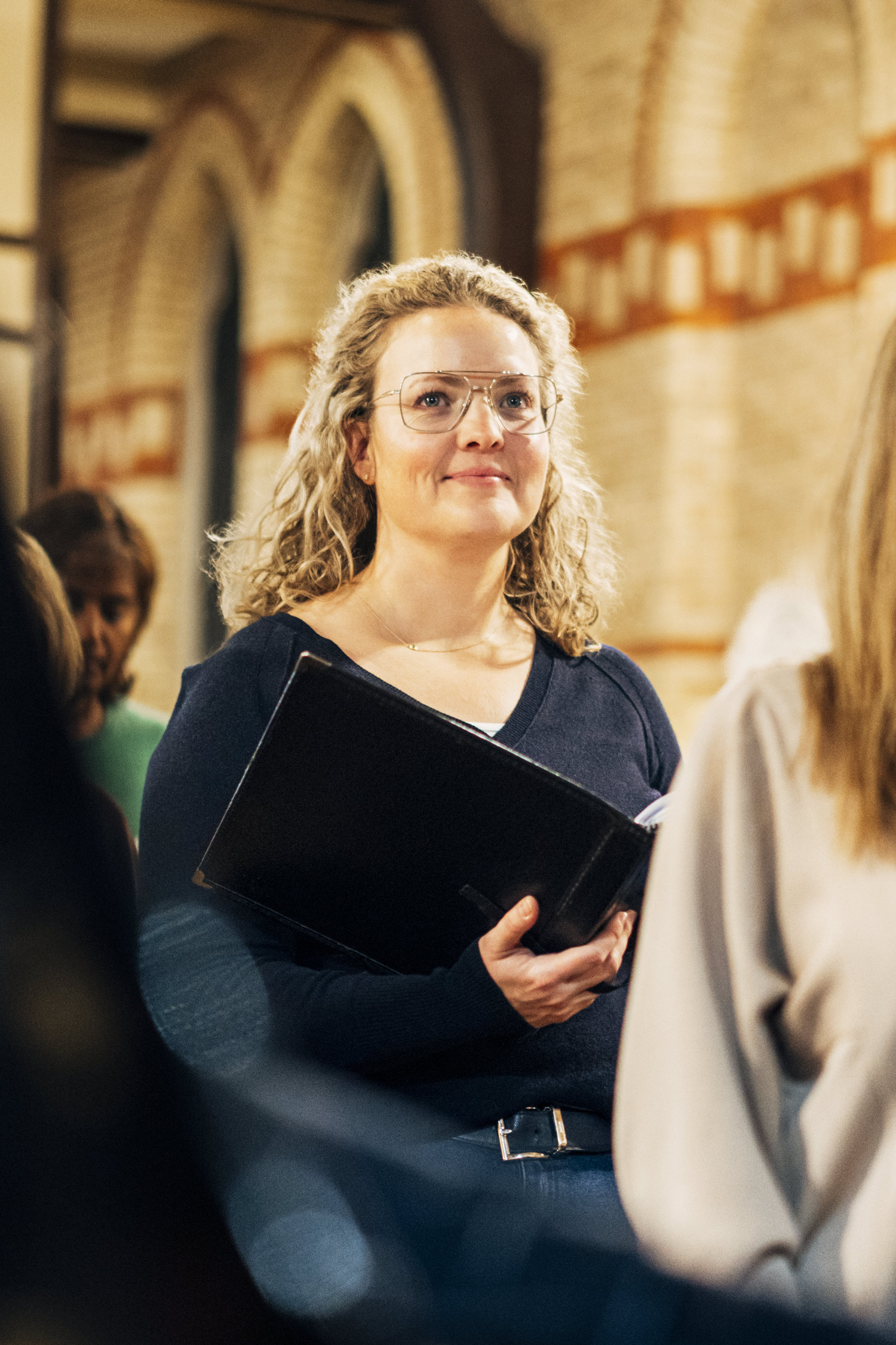 A woman holding a booklet with sheet music in it.