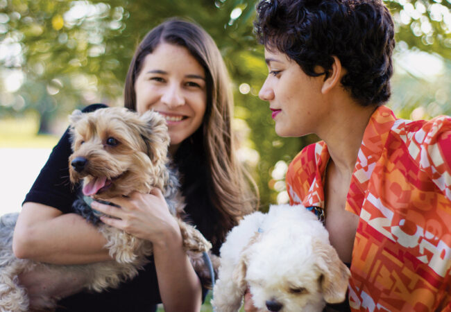 Two women holding their dogs