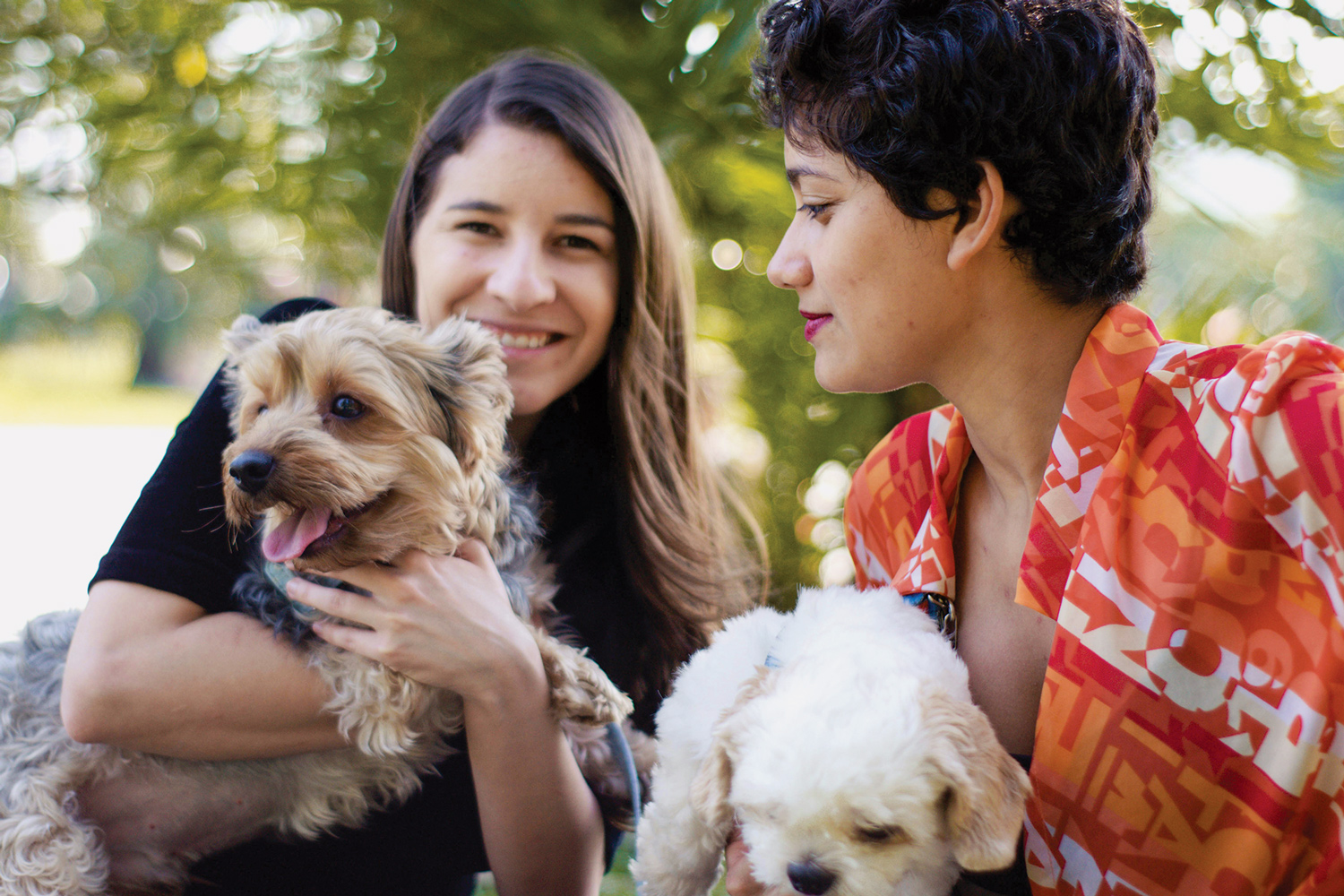 Two women holding their dogs