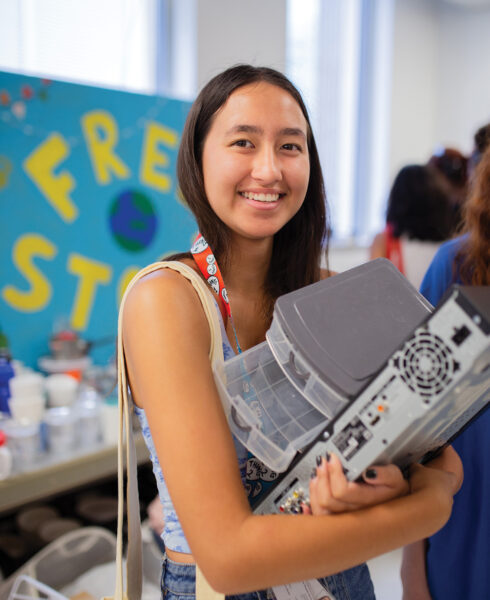 A student holds on to items obtained at the free store including a plastic organizer.