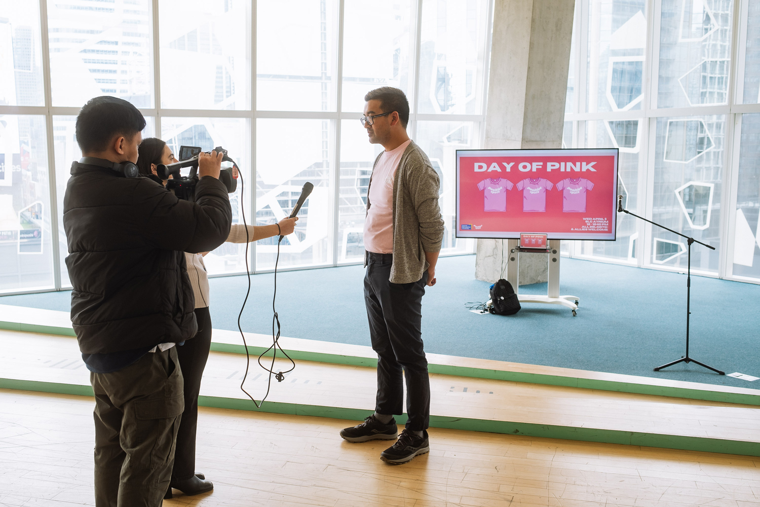 Dan Cantiller, Positive Space co-chair, wearing a pink shirt, being interviewed on camera.