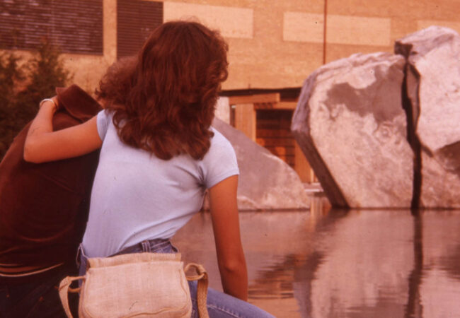An early photo of a couple sitting along the edge of Lake Devo, looking towards the pond.