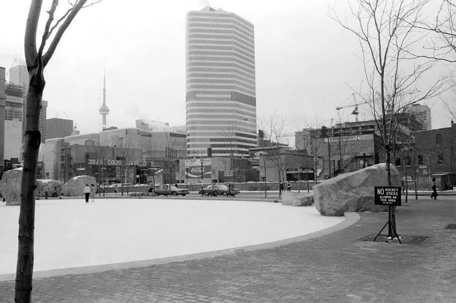 A black and white photo of Lake Devo in 1981 against the backdrop of a much different looking city, showing a view of the CN tower and Coles bookstore to the left.