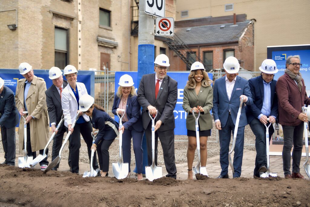 TMU community members dig their shovels into the ground at the groundbreaking event for the Student Wellbeing Centre.