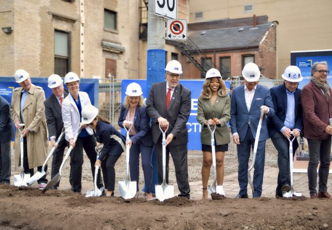 TMU community members dig their shovels into the ground at the groundbreaking event for the Student Wellbeing Centre.