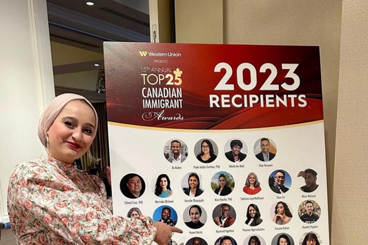 Hanen Namaa points to a photo of herself in a poster of the Top 25 Canadian Immigrant Award recipients.