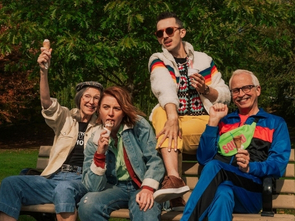 Four people, including two young adults and two older adults, sit on a bench smiling for a photo.