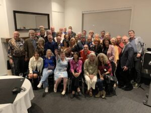 Dozens of adults smile and pose for a group photo.