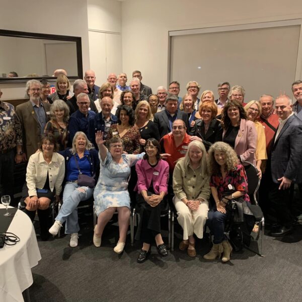 Dozens of adults smile and pose for a group photo.