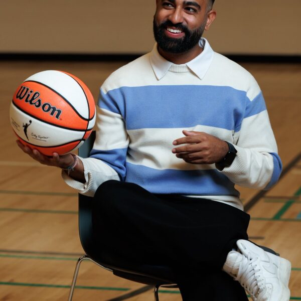 Kishan Mistry smiling while seated with a basketball in his hand.