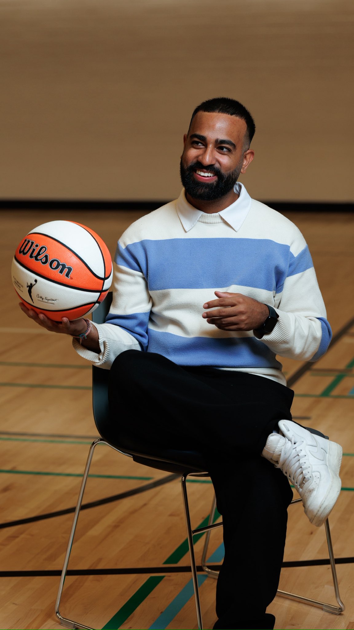Kishan Mistry smiling while seated with a basketball in his hand.