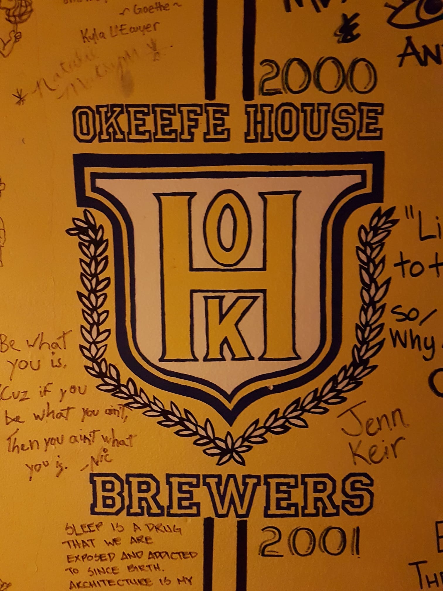 The O’Keefe House logo painted on a wall in the residence surrounded by hand-written messages and signatures.