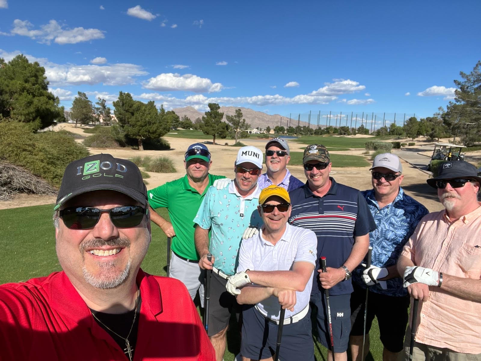 A group of men in their 50s and 60s pose for a photo on a golf course.
