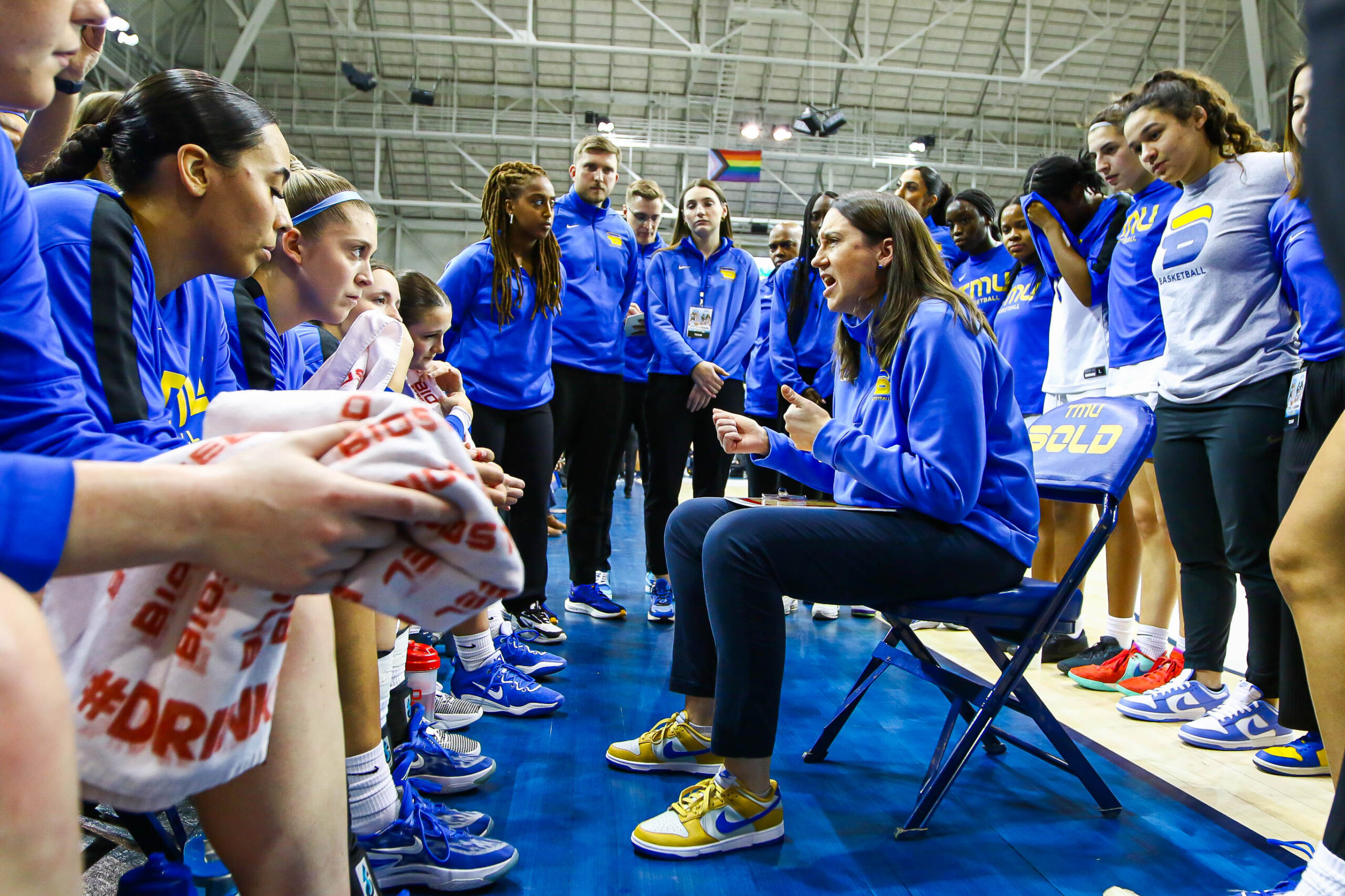 Carly Clarke surrounded by TMU Bold players as she speaks to them in a huddle.