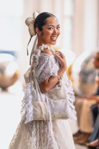 A model wears a pale textured runway look and carries one of Tristanne Lovetana’s sculptural pillow purses at New York Fashion Week.