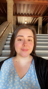 Marienza Miserere takes a selfie indoors, wearing a light blue patterned top and black cardigan.
