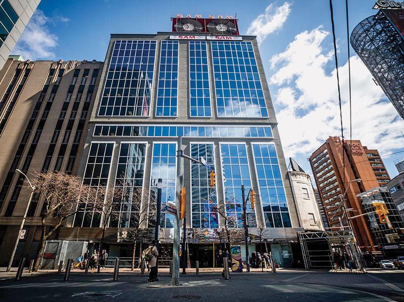 Street-level view of a tall glass-fronted TMU building in downtown Toronto.