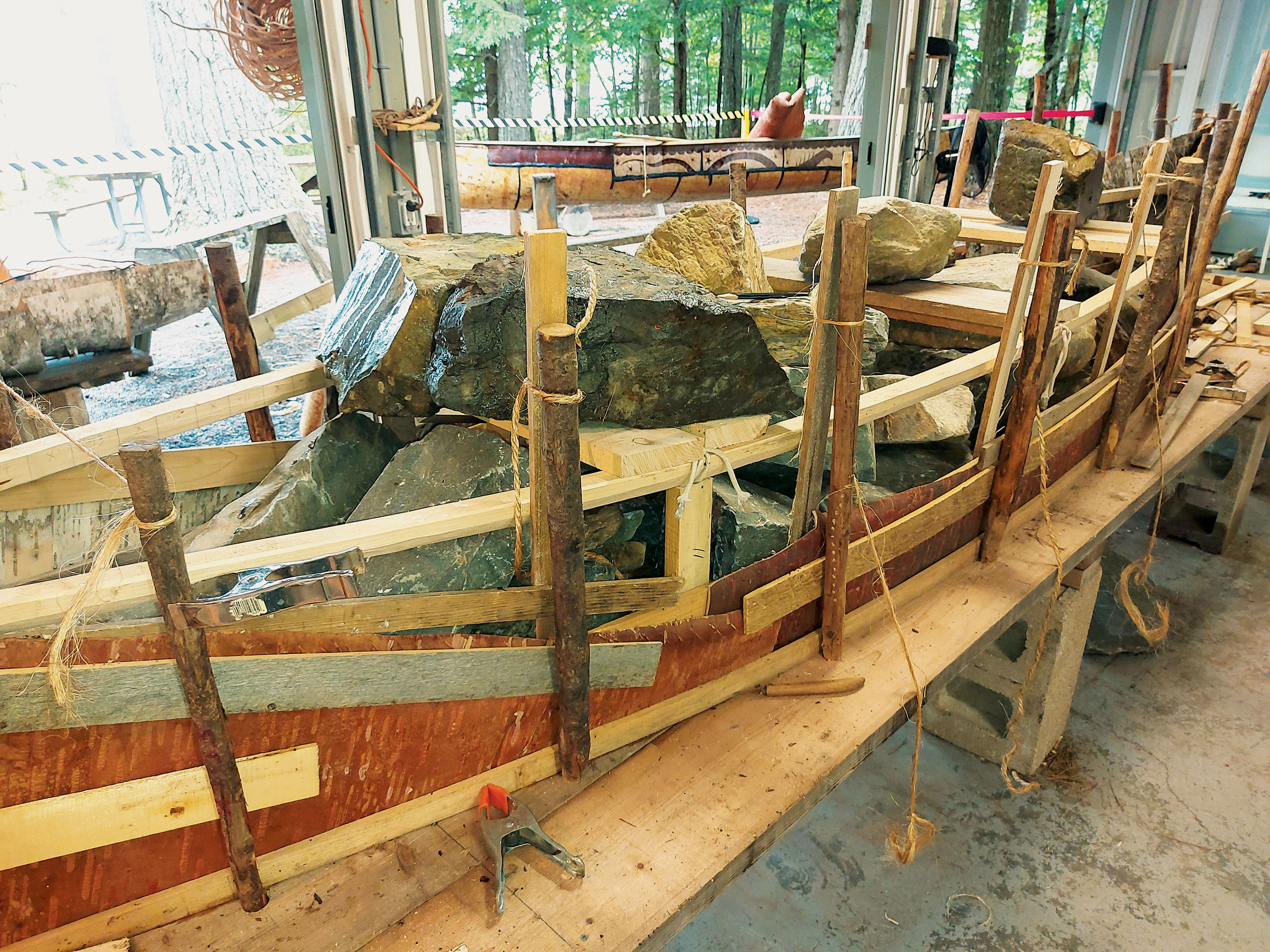 Rocks are weighing down the canoe frame that’s in the process of being built.