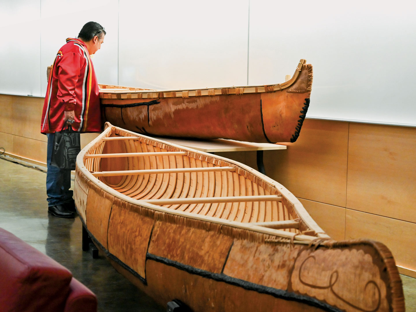 A man looking at the inside of a canoe on display.